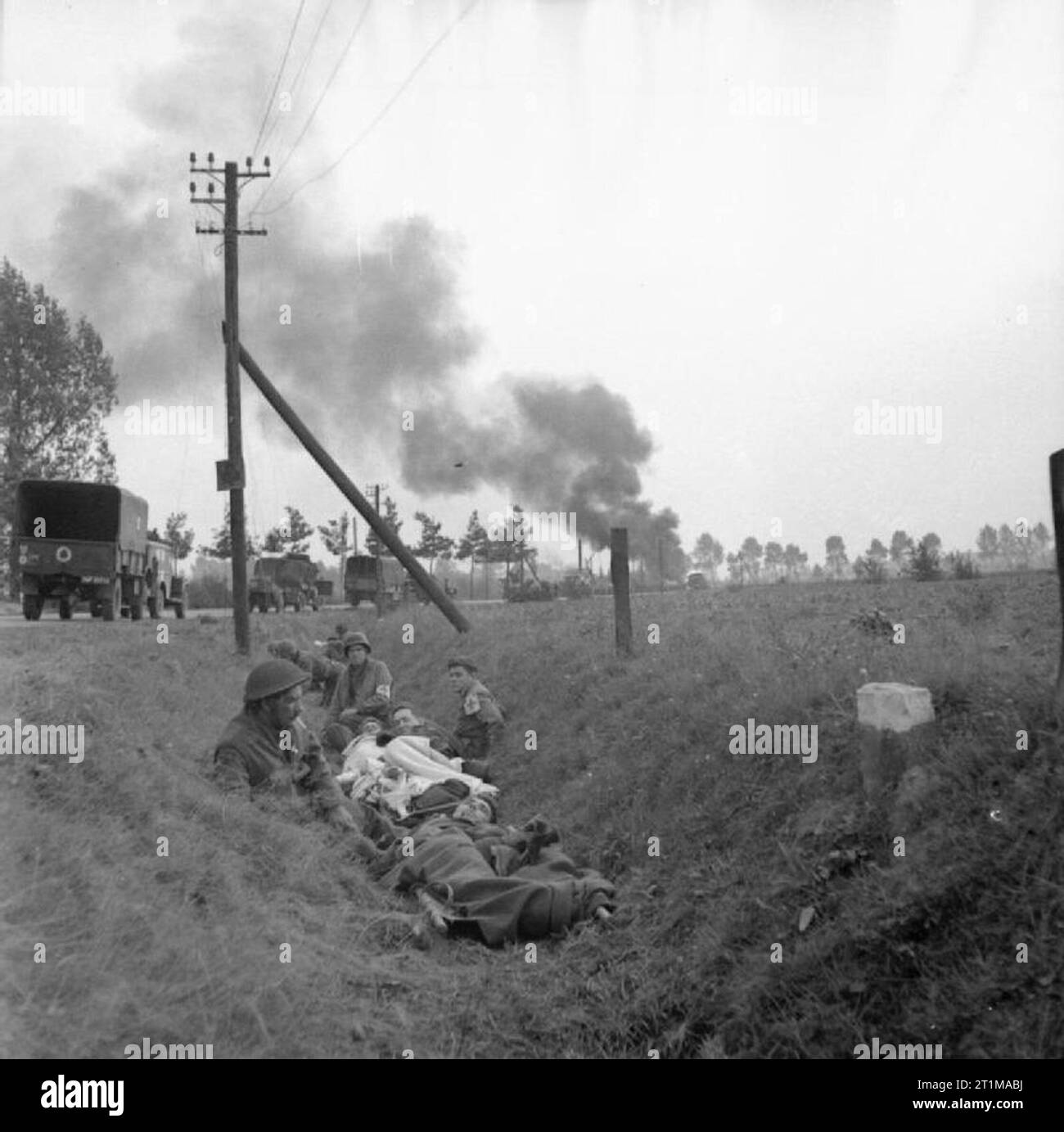 L'Esercito Britannico nel nord-ovest d'Europa 1944-45 un convoglio di camion sotto l'artiglieria nemica e colpi di mortaio sulla strada tra il Figlio e Eindhoven, 20 settembre 1944. In primo piano americano e britannico rifugio medics con il ferito in un fosso. Foto Stock