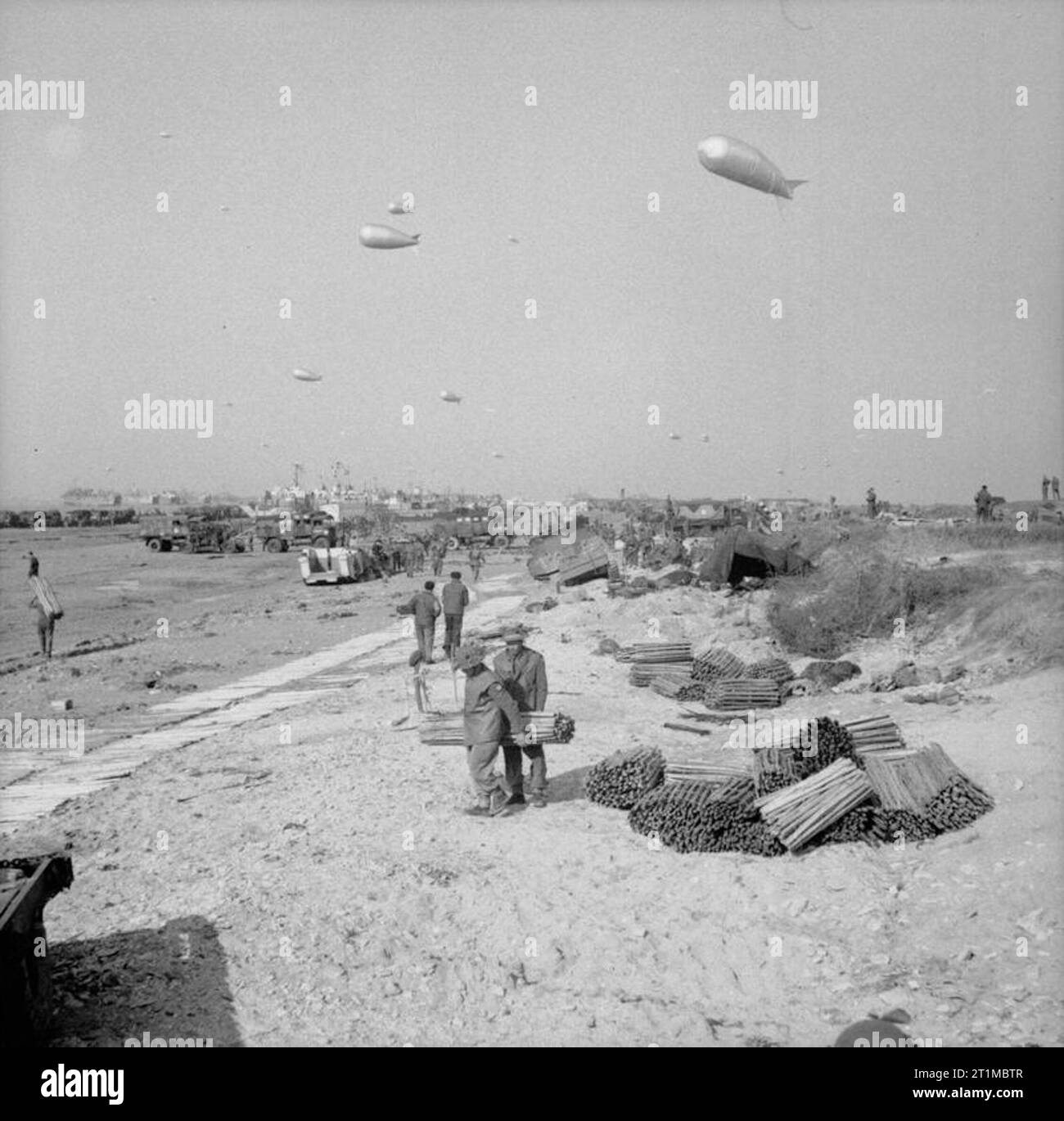 L'esercito britannico nella campagna di Normandia 1944 i veicoli e le forniture che arrivano a riva, con barrage palloncini sopra la spiaggia dorata, 7 giugno 1944. Foto Stock