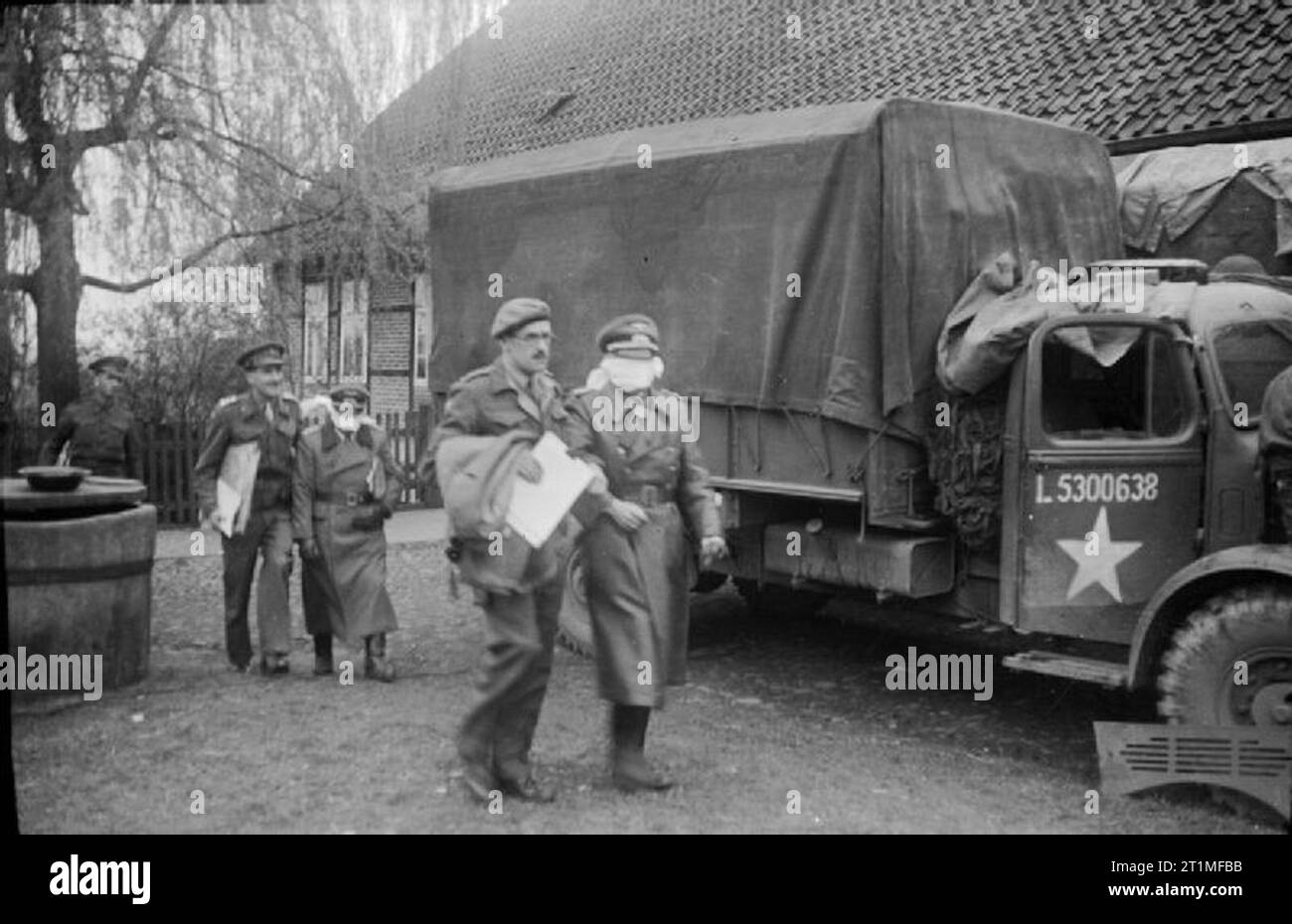 La liberazione di Bergen-belsen Campo di Concentramento, aprile 1945 due occhi bendati ufficiali tedeschi sono guidati attraverso le linee britanniche a Winsen previa notifica di avanzamento delle forze inglesi dell' esistenza di una malattia infettiva in Bergen-Belsen Campo di concentramento. I negoziati per arrivare a una tregua era stato concluso, a norma del quale è stato concordato che, al fine di contenere la malattia, a 48 chilometro quadrato area intorno al campo era di essere evacuato e posto fuori dai limiti di unità combattente di entrambi i lati diversi da quelli impegnati nel lavoro di soccorso al camp. Foto Stock