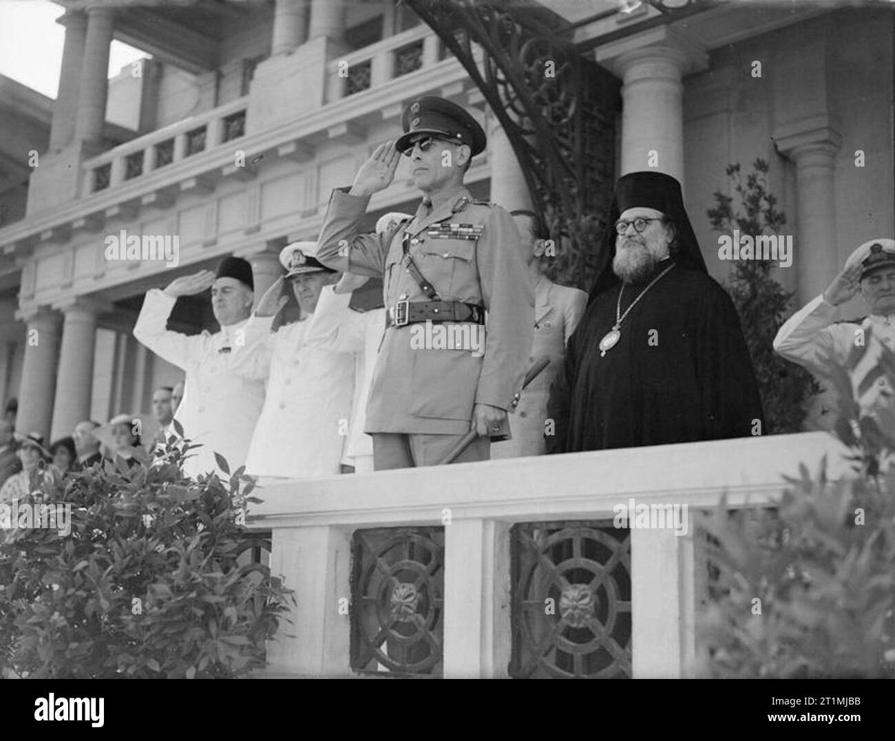 Il governo greco in esilio durante la Seconda Guerra Mondiale il re George del elleni tenendo la salute durante la riproduzione di un inno nazionale ad una parata militare di Alessandria. A sinistra (salutando) è Baker Pascià e accanto a lui, ammiraglio sir Henry Harwood. Secondo da destra è Christoforos, Patriarca greco-ortodosso per l'Africa. Foto Stock