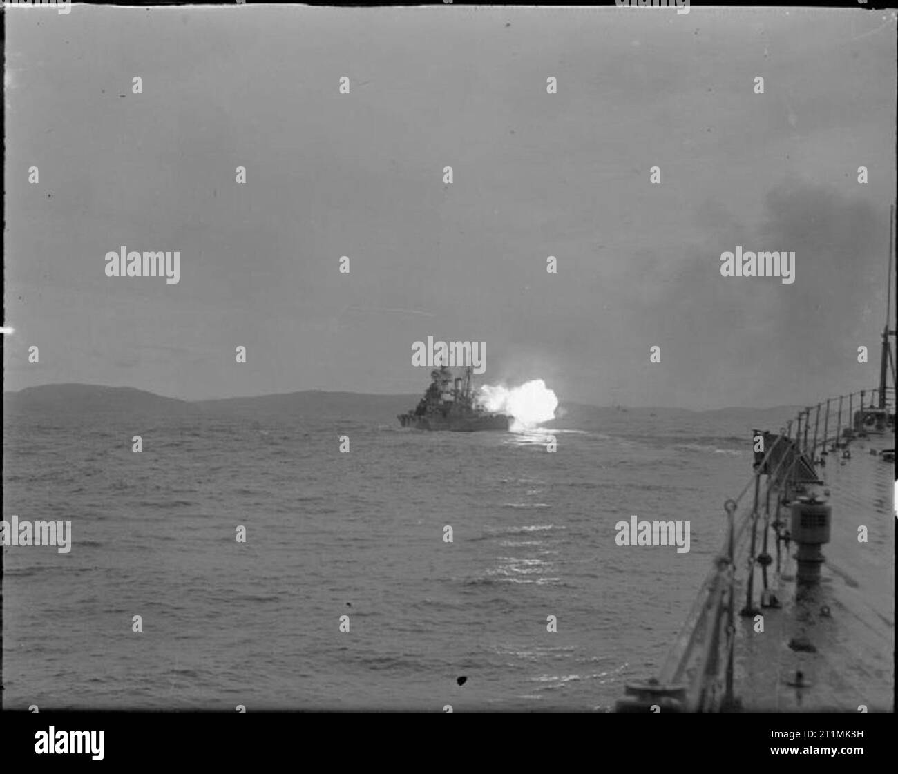 La Royal Navy durante la Seconda Guerra Mondiale una vista di HMS HOWE il suo lancio 14 pollici pistole vicino a Scapa Flow. Il flash brillante dei cannoni che precede il fumo di cordite dura solo per una frazione di secondo. Foto Stock