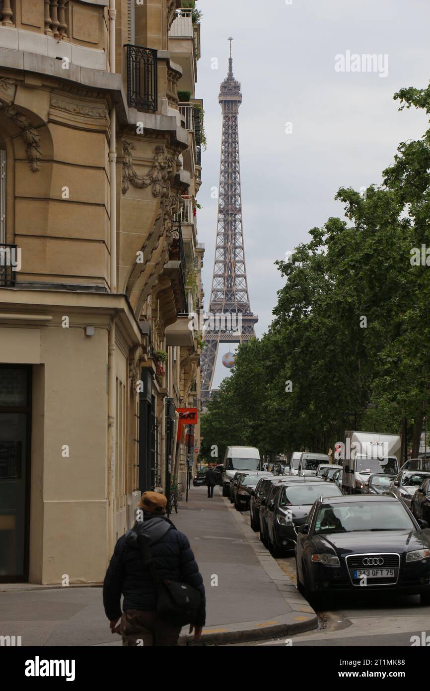 Una vista della Torre Eiffel incorniciata da strade distanti, accoccolata tra edifici e alberi Foto Stock