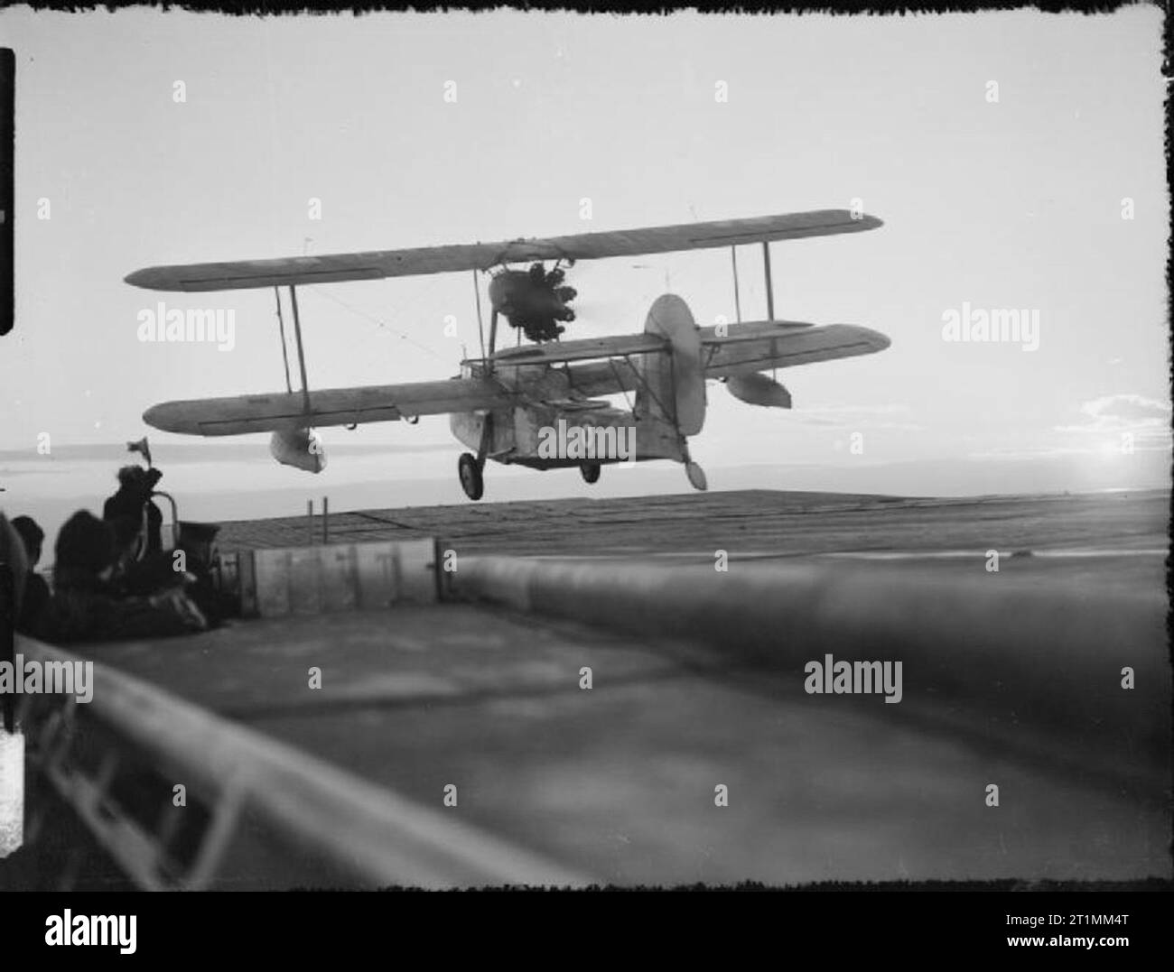 La Royal Navy durante la Seconda guerra mondiale Un Supermarine tricheco aeromobile Anfibio prende il largo all'alba da HMS ARGUS. Il profilarsi la figura con la bandiera sulla sinistra è il ponte di volo ufficiale, "Ali", che segnala i piloti che siano chiari per il decollo. Foto Stock