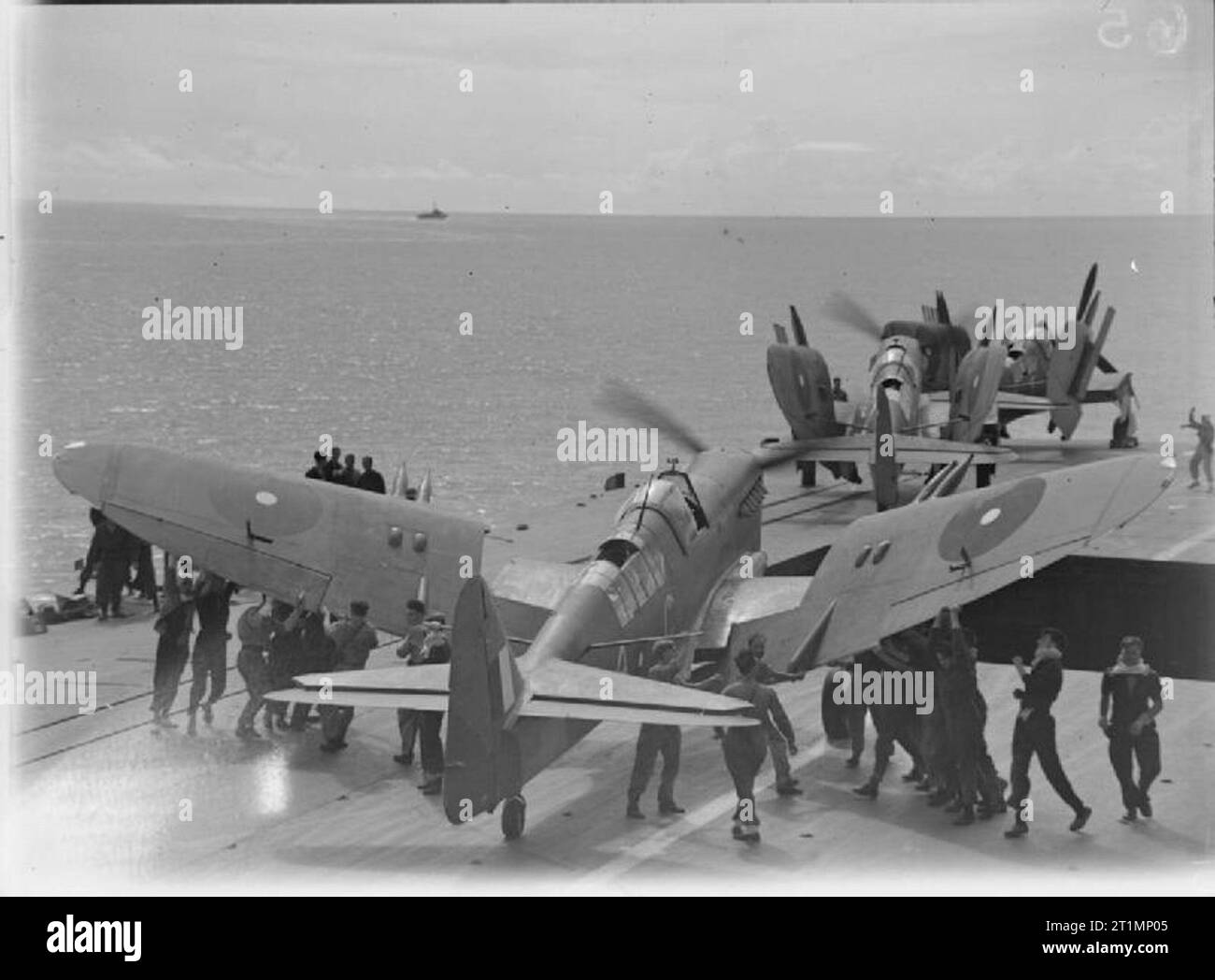 La Royal Navy durante la Seconda guerra mondiale uomini piegatura delle ali di un Fairey Firefly di 1770 Squadron, Fleet Air Arm a bordo HMS infaticabile sul volo di ritorno dal carrier-borne aerei sciopero sul giapponese raffineria di petrolio a Pangkalan Brandan, Sumatra. Le condizioni meteo erano eccellenti e tutto il peso di bombe e missili da Grumman vendicatori e Fairey lucciole cadde nell'area target. Il potente e di altri importanti impianti, insieme con i serbatoi di olio ed edifici, ricevuto direct hits. Foto Stock