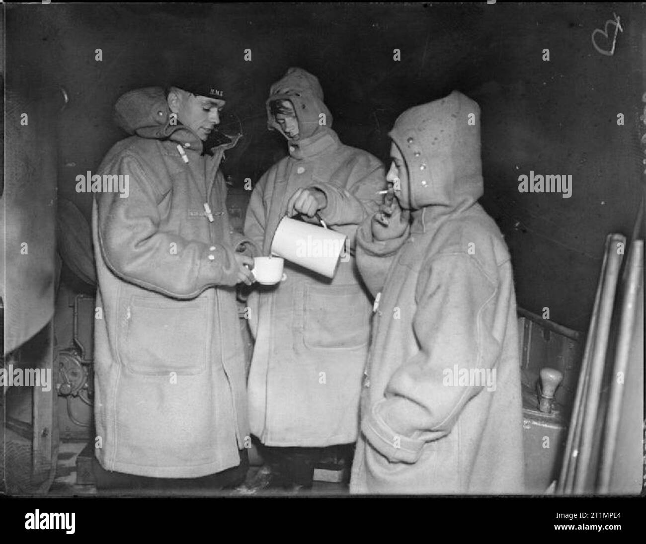 La Royal Navy durante la Seconda Guerra Mondiale il tè e una sigaretta è molto benvenuto nelle prime ore della mattina chill on board HMS JACKAL durante il periodo notturno esercizi. Uno degli uomini è versando gli altri una bevanda calda mentre un terzo ha un fumo. Foto Stock