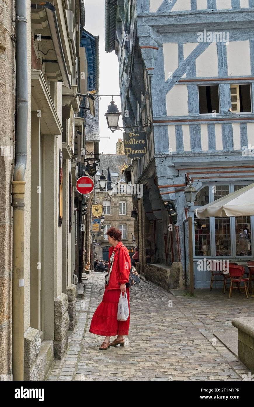 Dinan, Francia - giugno 2008: Lady in Red window shopping Place des Merciers, centro della città con strade acciottolate fiancheggiate da edifici medievali in legno Foto Stock