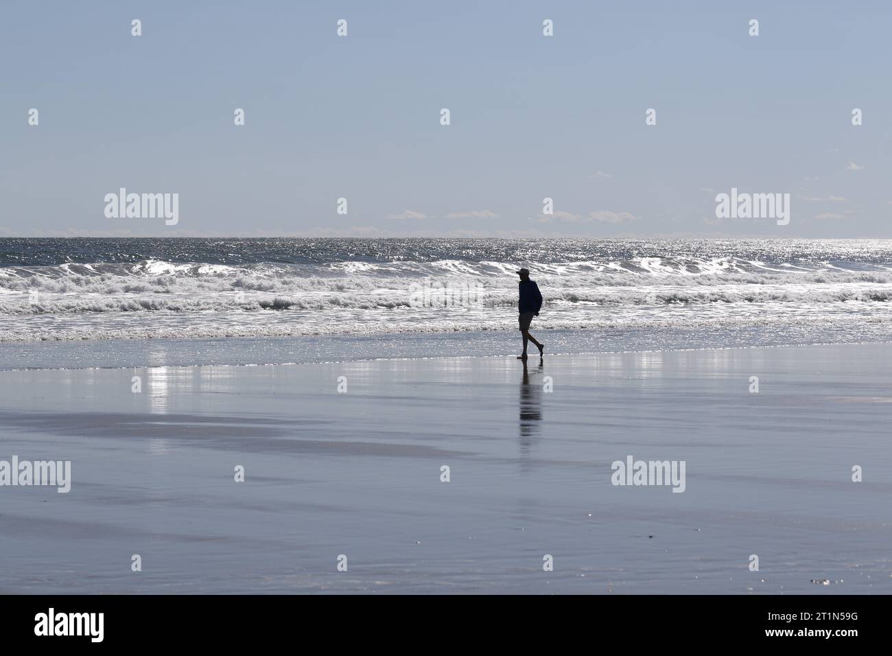 Un uomo in silhouette che cammina su Good Harbor Beach a Gloucester, Massachusetts Foto Stock