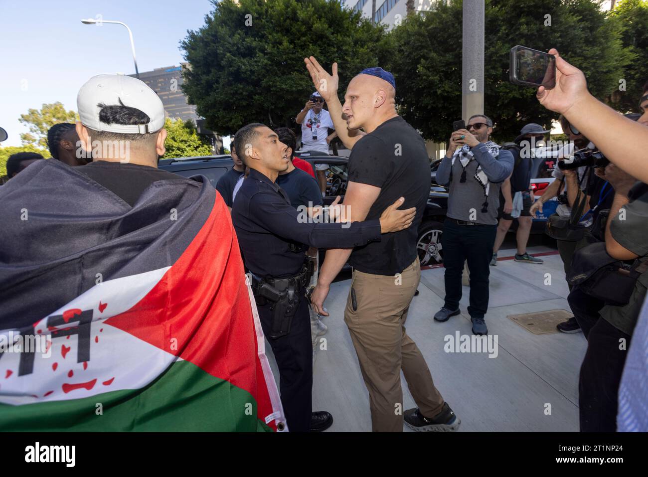 Los Angeles, California, USA. 14 ottobre 2023. Jeffrey Rosenberg, che è ebreo, parla con un'area di ufficiali della polizia di Los Angeles dopo che i manifestanti pro-Palestina gli hanno portato via la sua bandiera israeliana mentre marciavano lungo Wilshire Boulevard fino al Federal Building per protestare a sostegno dei palestinesi catturati nella guerra israelo-Hamas. (Immagine di credito: © Jill Connelly/ZUMA Press Wire) SOLO USO EDITORIALE! Non per USO commerciale! Foto Stock