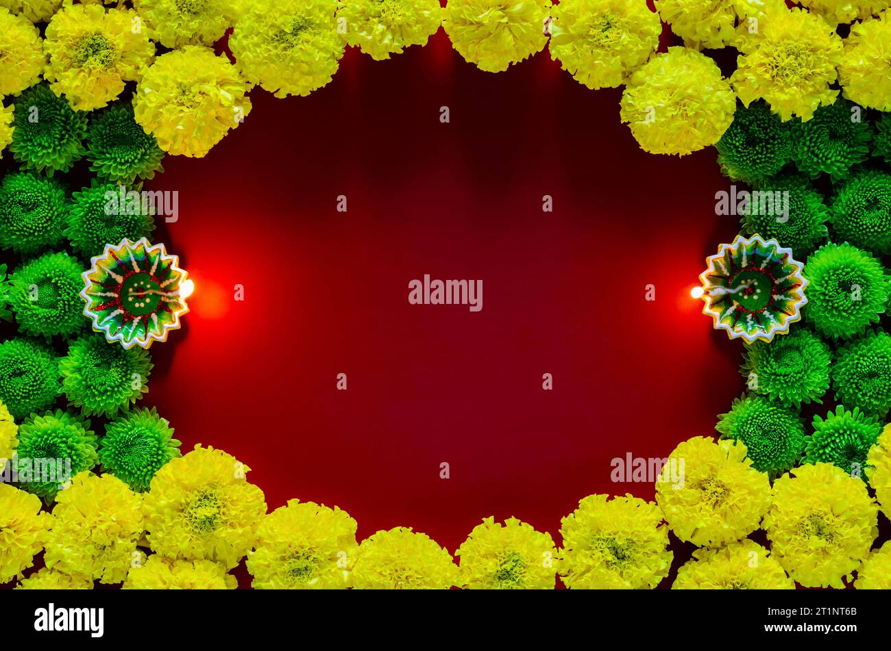 Lampade diya in argilla accese per festeggiare il festival Diwali con fiori colorati su sfondo rosso scuro vuoto. Foto Stock