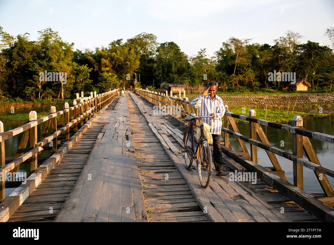 Uomo del posto con una bicicletta in piedi su un vecchio ponte di legno nell'isola Majuli ad assam, india Foto Stock