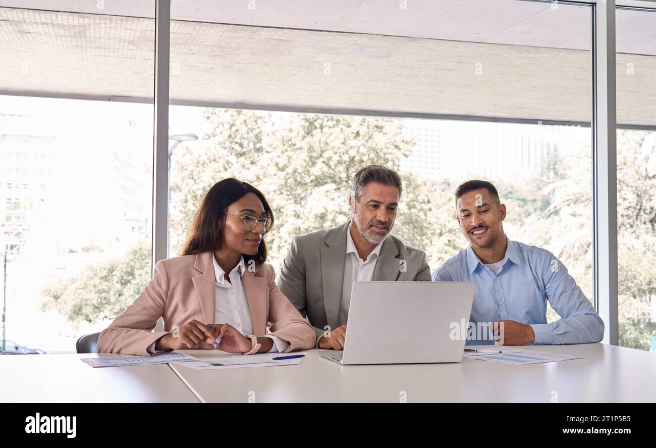 Tre dipendenti aziendali che utilizzano un computer portatile che lavorano in ufficio durante una riunione. Foto Stock