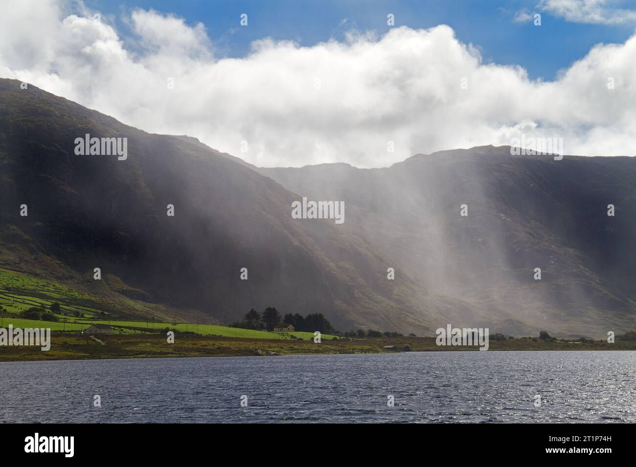 Piove sopra Cloon Lough e le montagne Kerry, Irlanda, sole su un prato e una fattoria Foto Stock