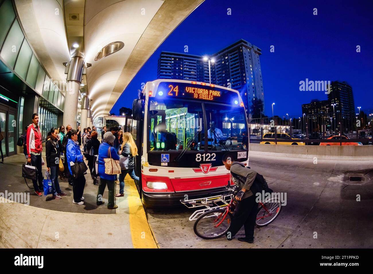 Persone che salgono a bordo di un autobus pubblico della Toronto Transit Commission nella stazione di Victoria Park. Un uomo mette una bicicletta nel portapacchi anteriore del veicolo a motore Foto Stock