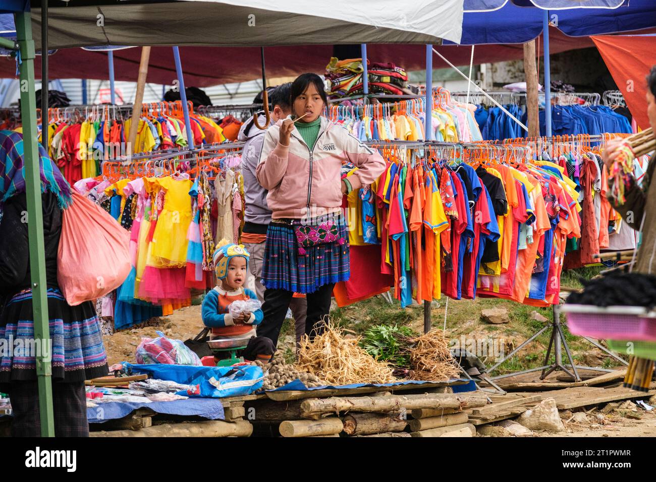 CAN Cau Market Scene, Vietnam. Giovane donna Hmong che vende abbigliamento in stile occidentale. Provincia di Lao Cai. Foto Stock