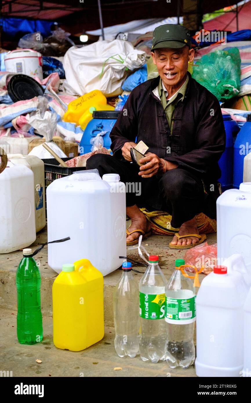 BAC ha, Vietnam. Sunday Market Scene. Uomo che vende bevande alcoliche fatte in casa. Provincia di Lao Cai. Foto Stock