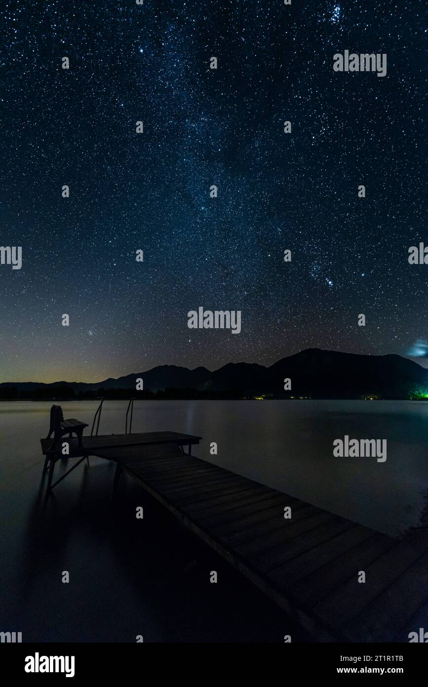 Molo di legno sulla riva del lago Kochel nelle montagne bavaresi sotto un cielo stellato notturno, Germania Foto Stock