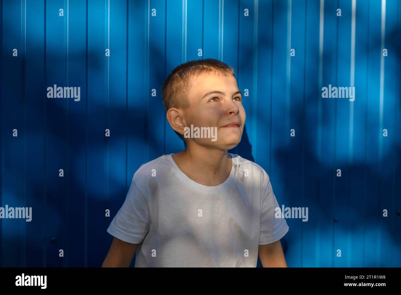 Dreams on the Horizon: Lo sguardo speranzoso di un ragazzo contro il muro Blu Foto Stock