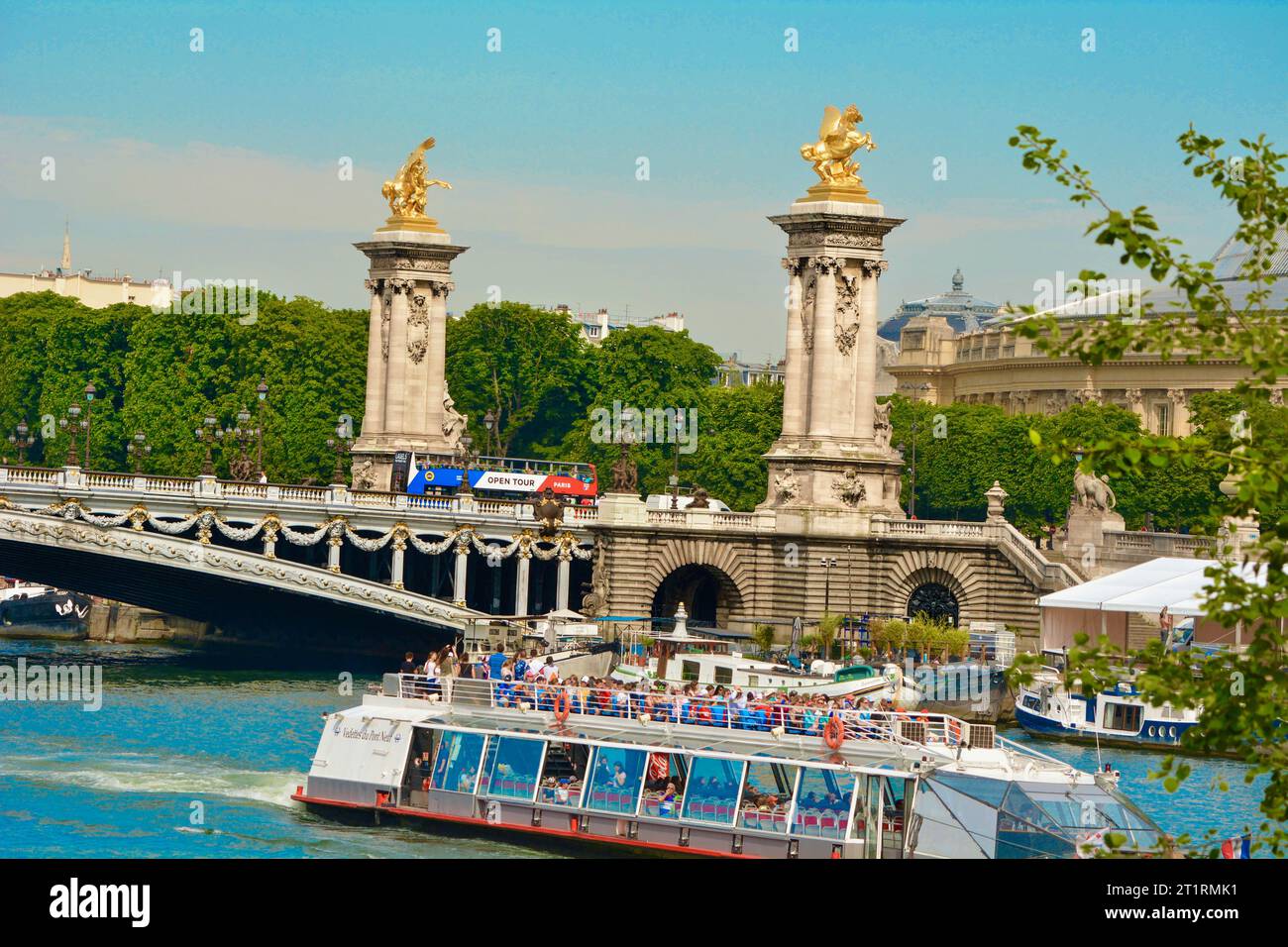 L'affascinante ponte Alexander III a Parigi, in Francia, con sculture in oro, offre viste mozzafiato e ambientazioni romantiche, battelli fluviali sotto un cielo estivo blu Foto Stock