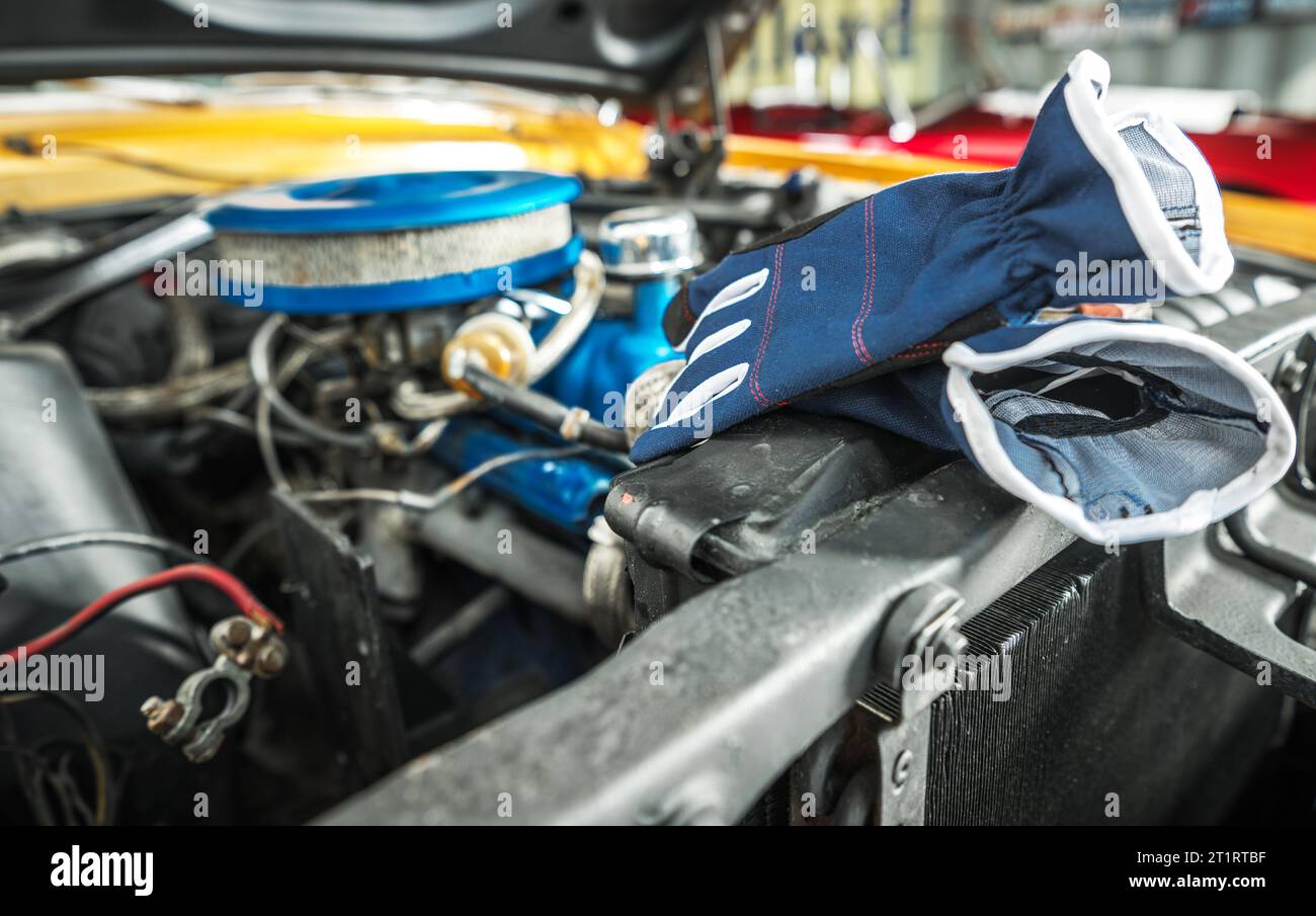 Guanti di protezione posizionati accanto al vano motore dell'auto classica durante il processo di ripristino dell'auto. Foto Stock