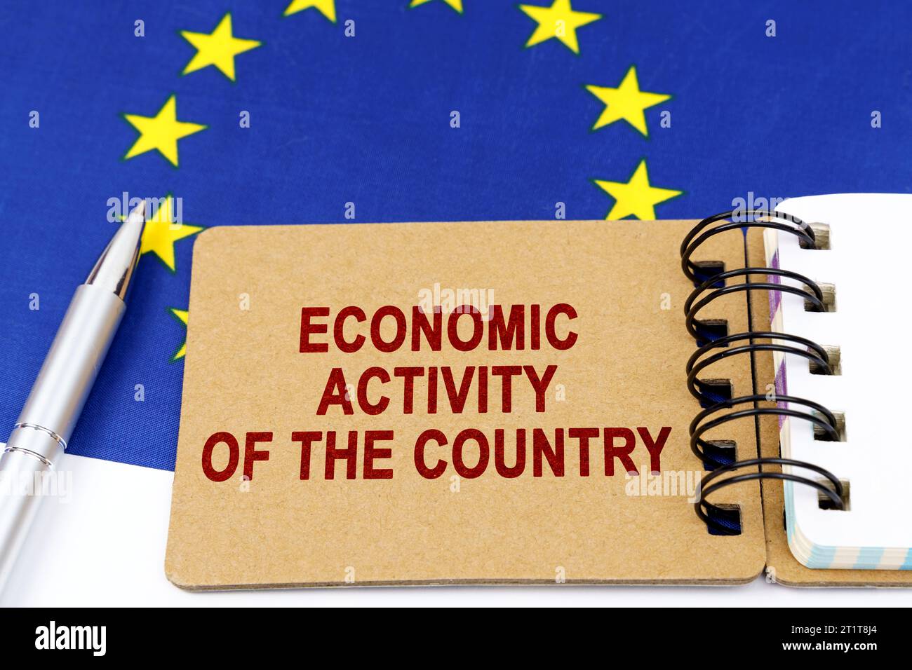 Economia e finanza. Sulla bandiera dell'Unione europea si trovano una penna e un blocco note con l'iscrizione "attività economica del paese" Foto Stock