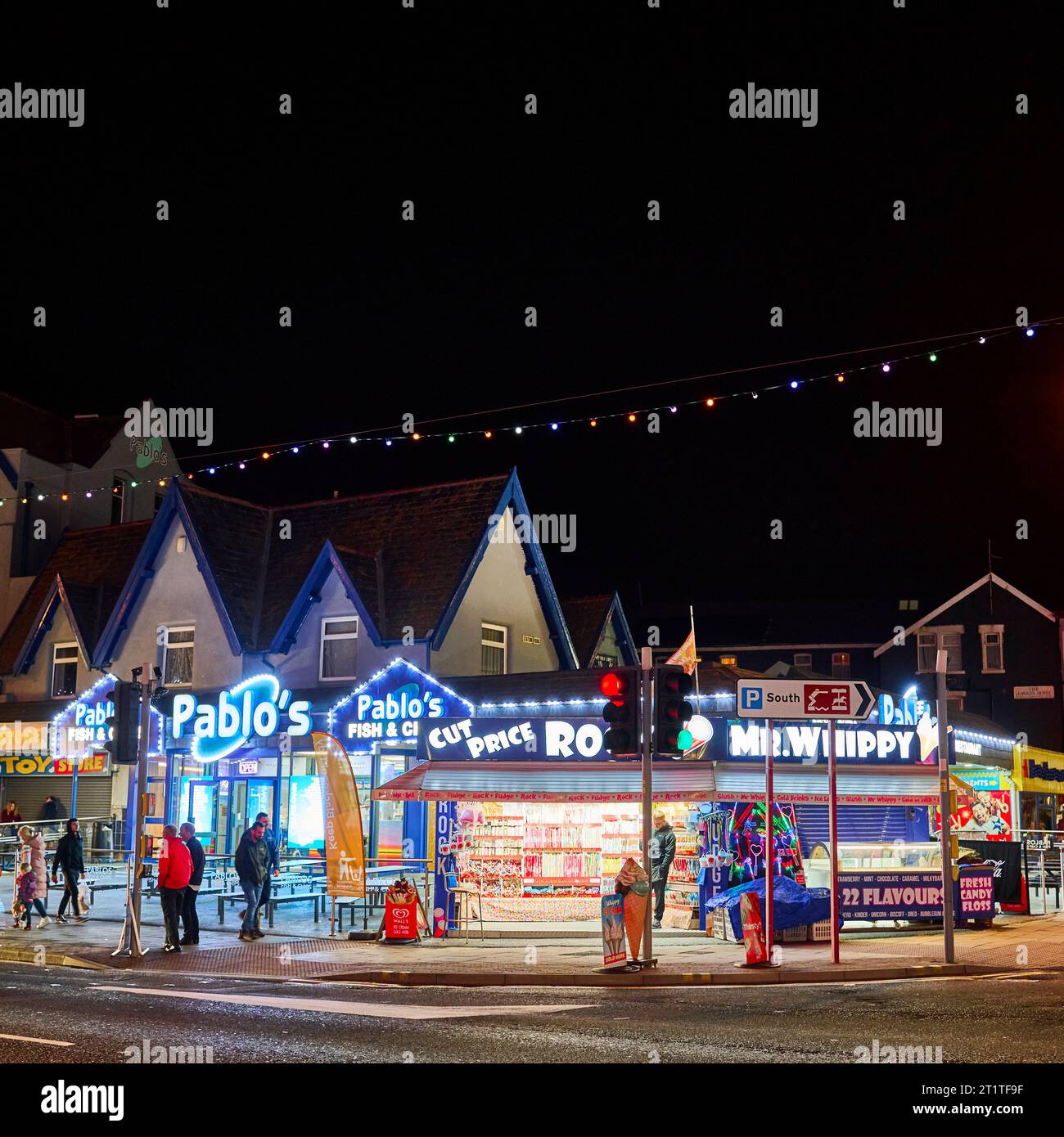 Durante le illuminazioni, c'è un ristorante con bancarelle di roccia e fish and chips all'angolo di una strada a Blackpool Foto Stock
