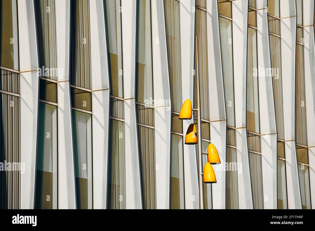 Luci stradali gialle contro un blocco di uffici in cemento e vetro Foto Stock