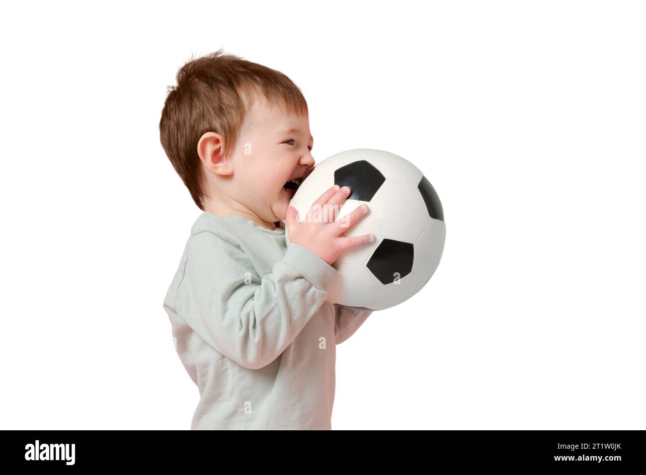 Bimbo allegro con una palla da calcio su uno studio, isolato su sfondo bianco. Bambino che tiene in mano una palla sportiva, isolato su uno schienale bianco Foto Stock