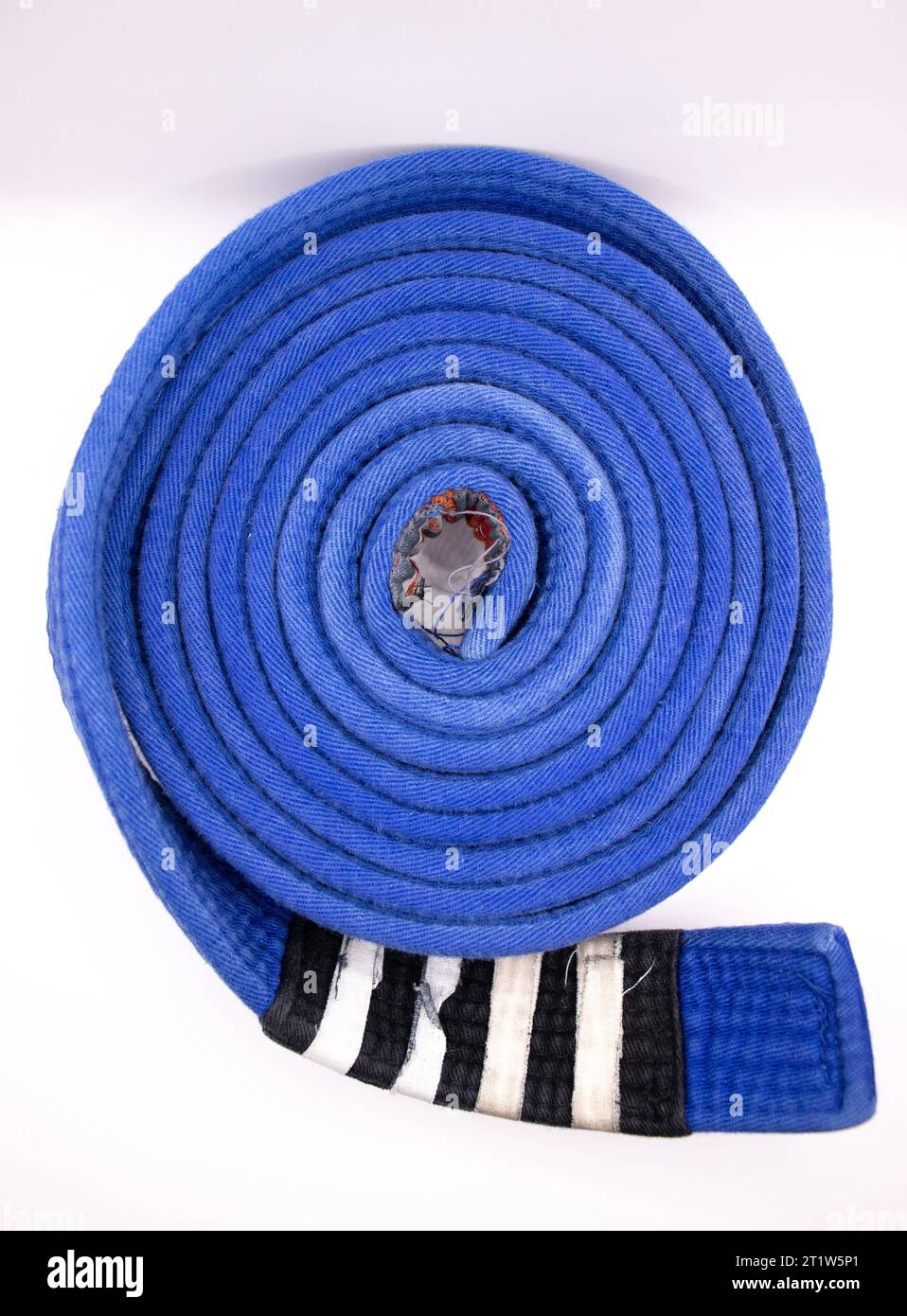 Una cintura brasiliana jiu jitsu arrotolata blu con quattro strisce Foto Stock