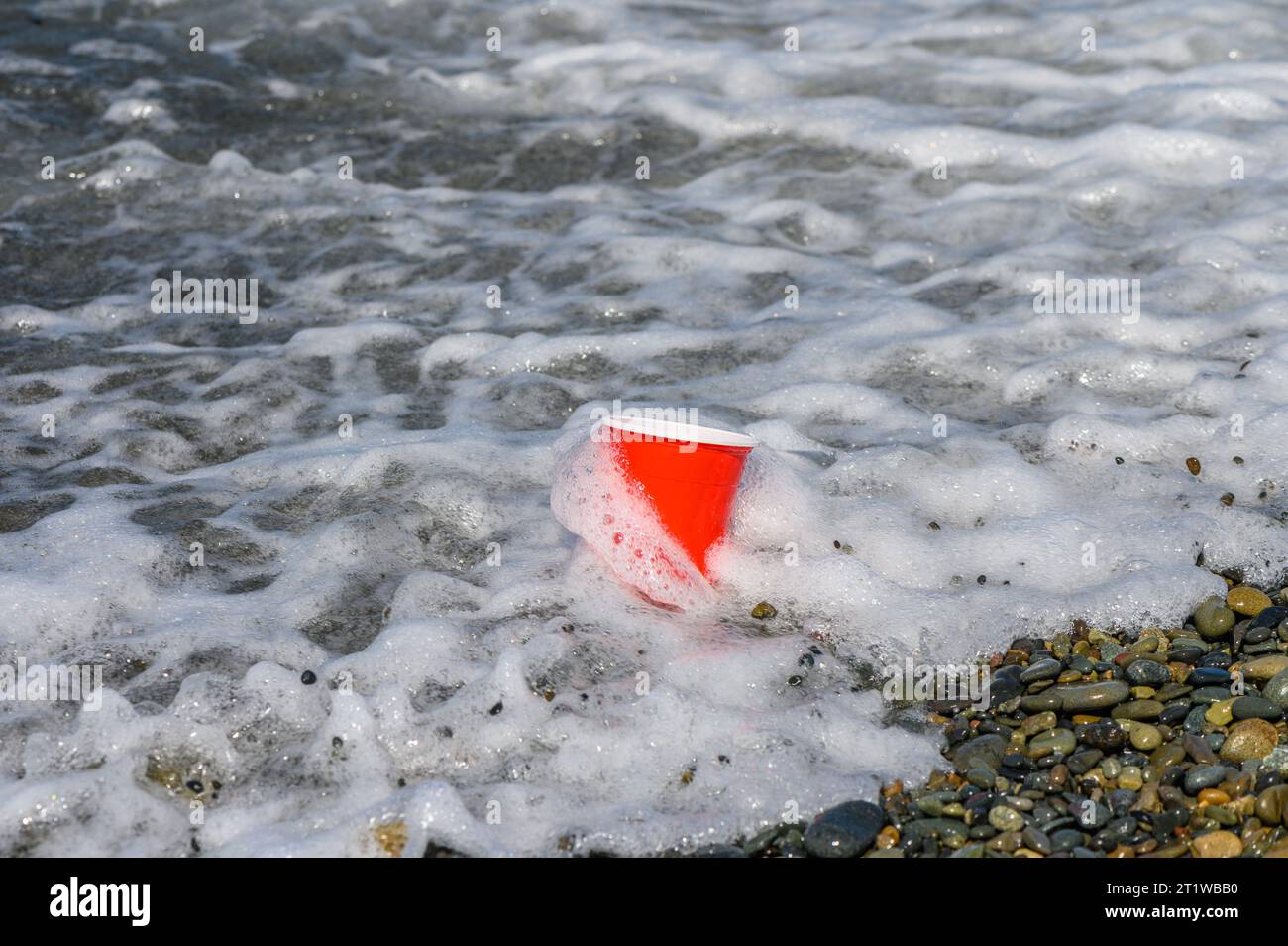 Vetro di plastica rosso di spazzatura lavato sulla spiaggia mediterranea 4 Foto Stock