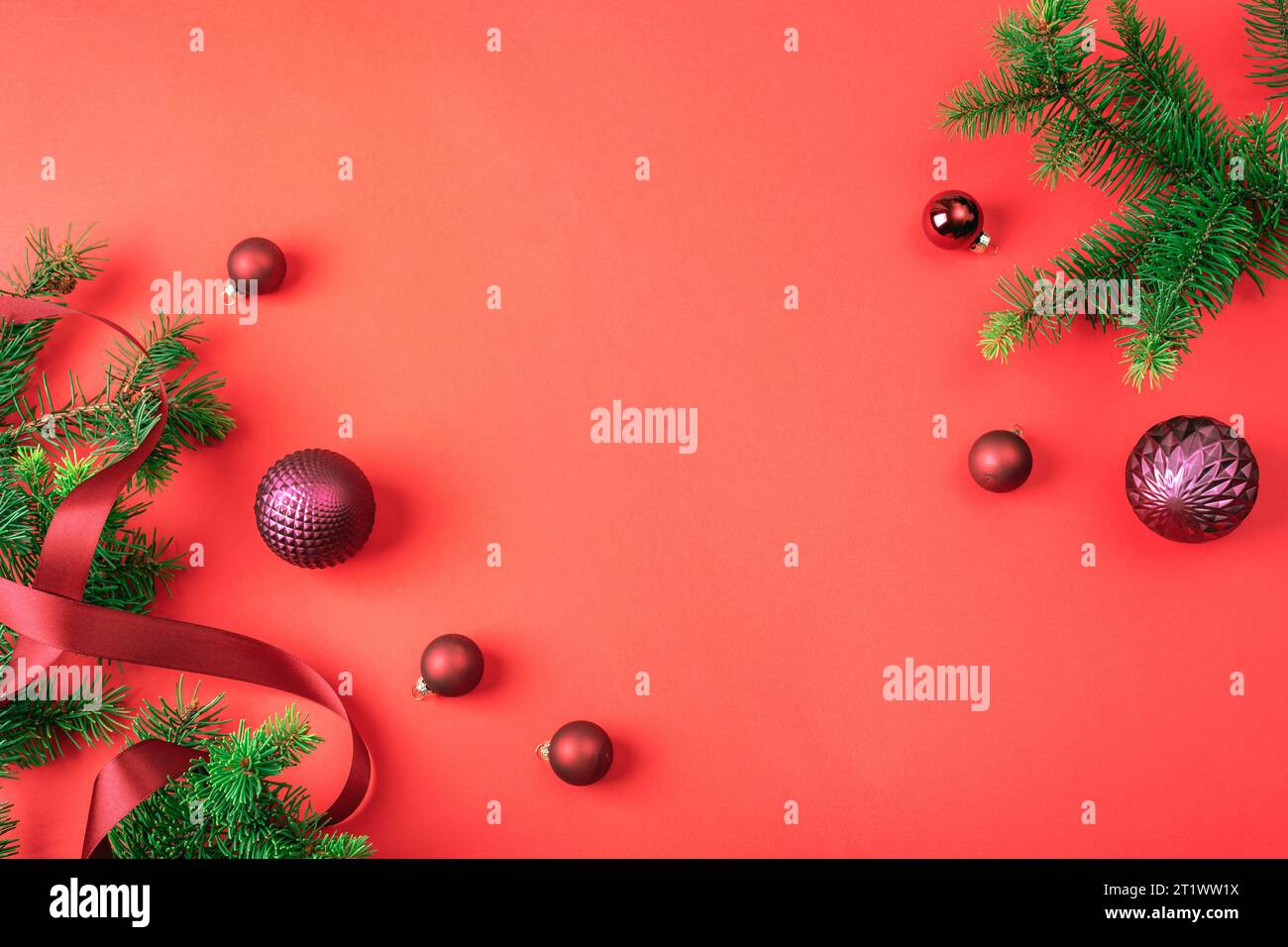 Rami di abete e palline di Natale su sfondo rosso. Vacanze invernali. Vista dall'alto, base piatta, spazio di copia. Foto Stock