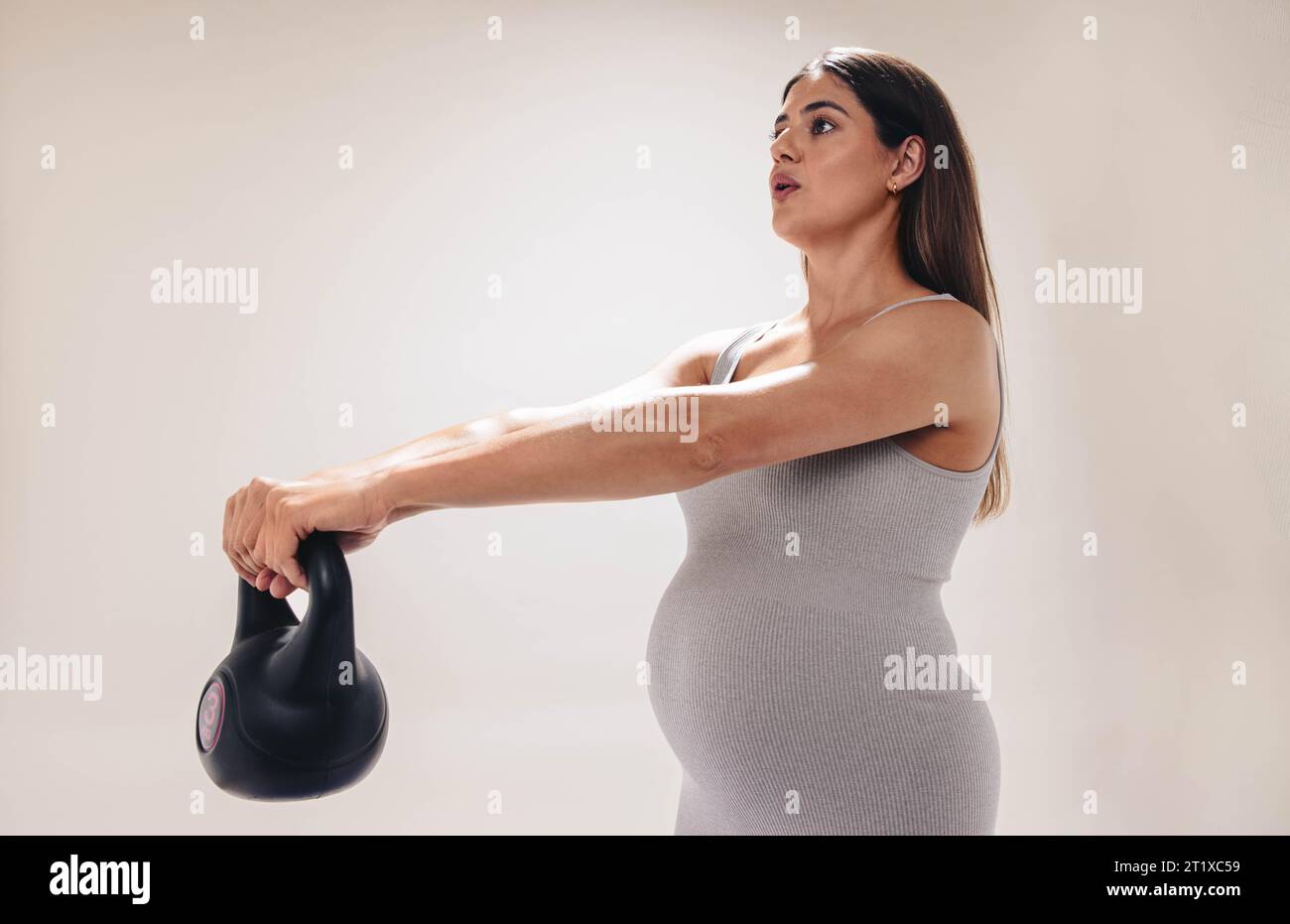 la donna incinta nel suo terzo trimestre si concentra sul fitness e il benessere. Solleva pesi, stretches ed esercizi per un corpo sano durante la gravidanza Foto Stock
