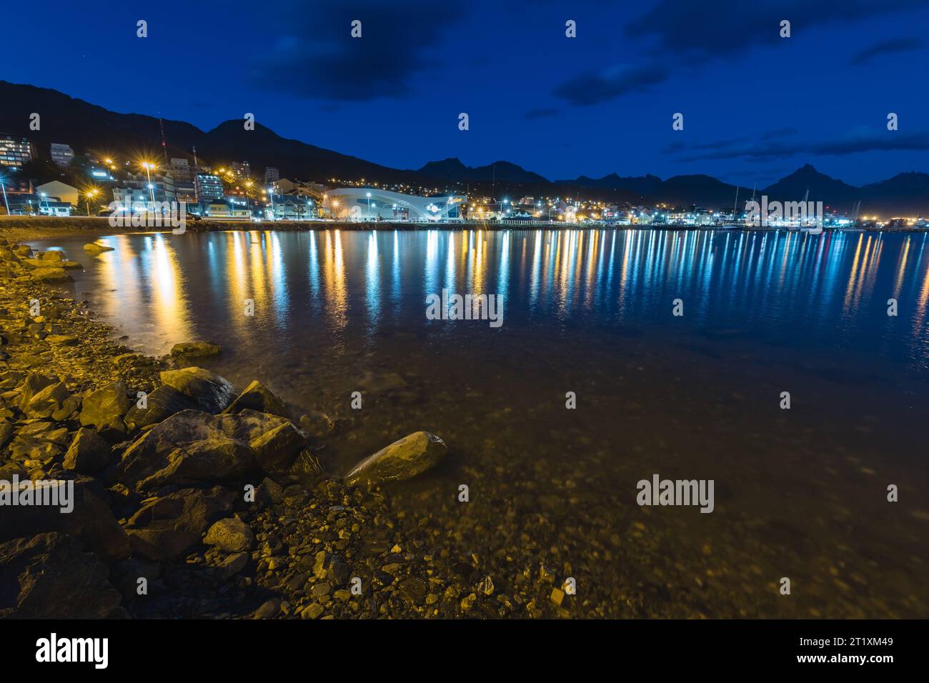 Inizio dell'ora blu dalla costa di Ushuaia, con le luci della città completamente accese Foto Stock