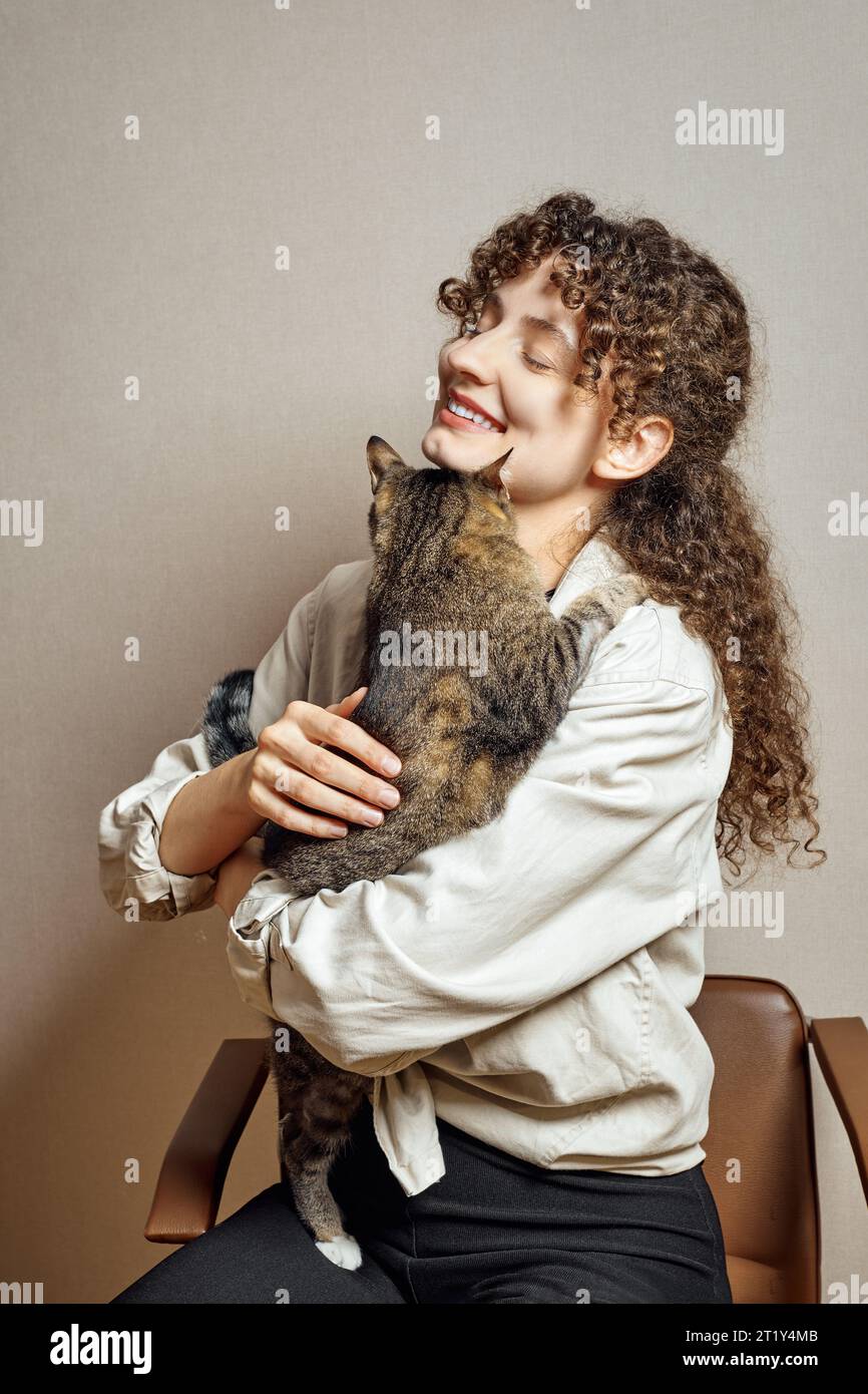 Una giovane donna carina cerca di tenere il suo gatto irrequieto nelle sue mani Foto Stock