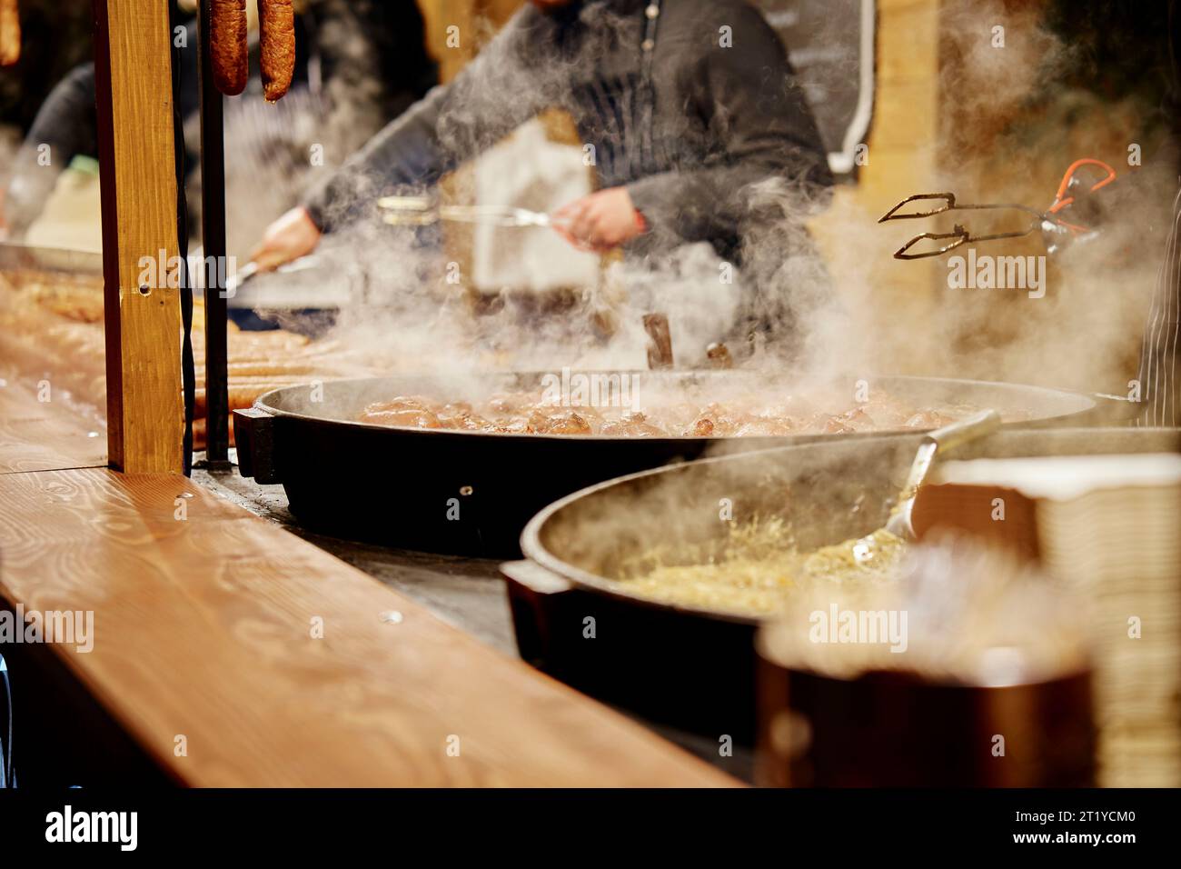 Processo di cottura di cibo di strada all'aperto. Padella con piatti fritti. Fiera di Natale nella piazza principale di Breslavia Foto Stock