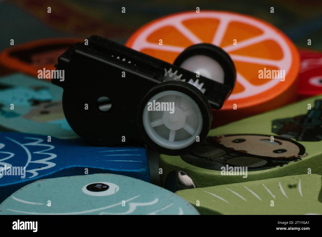 Una parte meccanica rotta di un giocattolo per bambini sulla sommità di un giocattolo puzzle luminoso Foto Stock