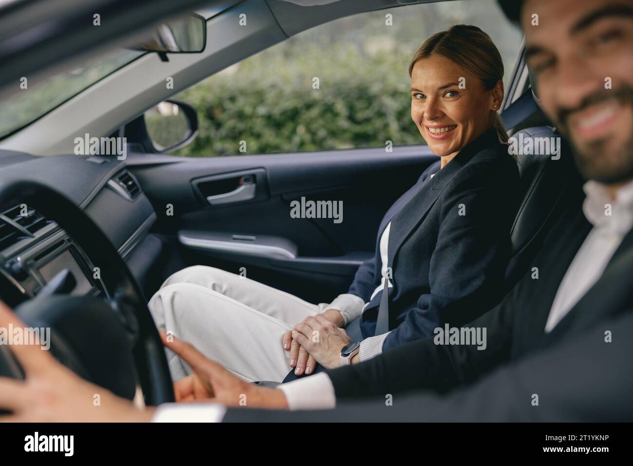 Due colleghi d'affari positivi che si adattano al carpooling viaggiano per lavorare insieme e avere un aspetto più accattivante Foto Stock