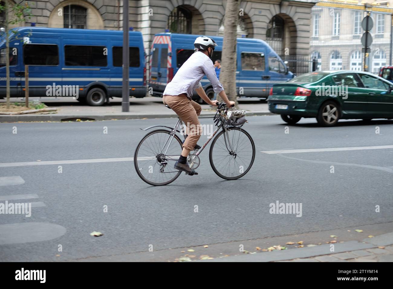 Uomo su una vecchia bici da strada con manubrio a barre piatte, camicia in cotone e pantaloni marroni, viaggio serale sul Boulevard du Palais, Parigi, Francia Foto Stock