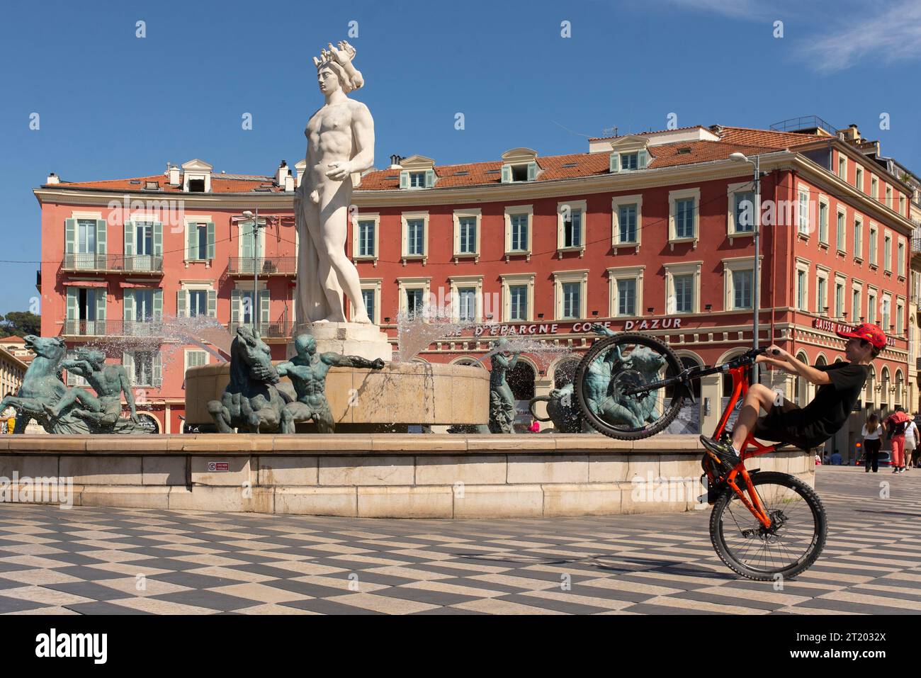 Un bambino in bicicletta a rotelle che passa accanto alla statua di Apollo e alla fontana Foto Stock