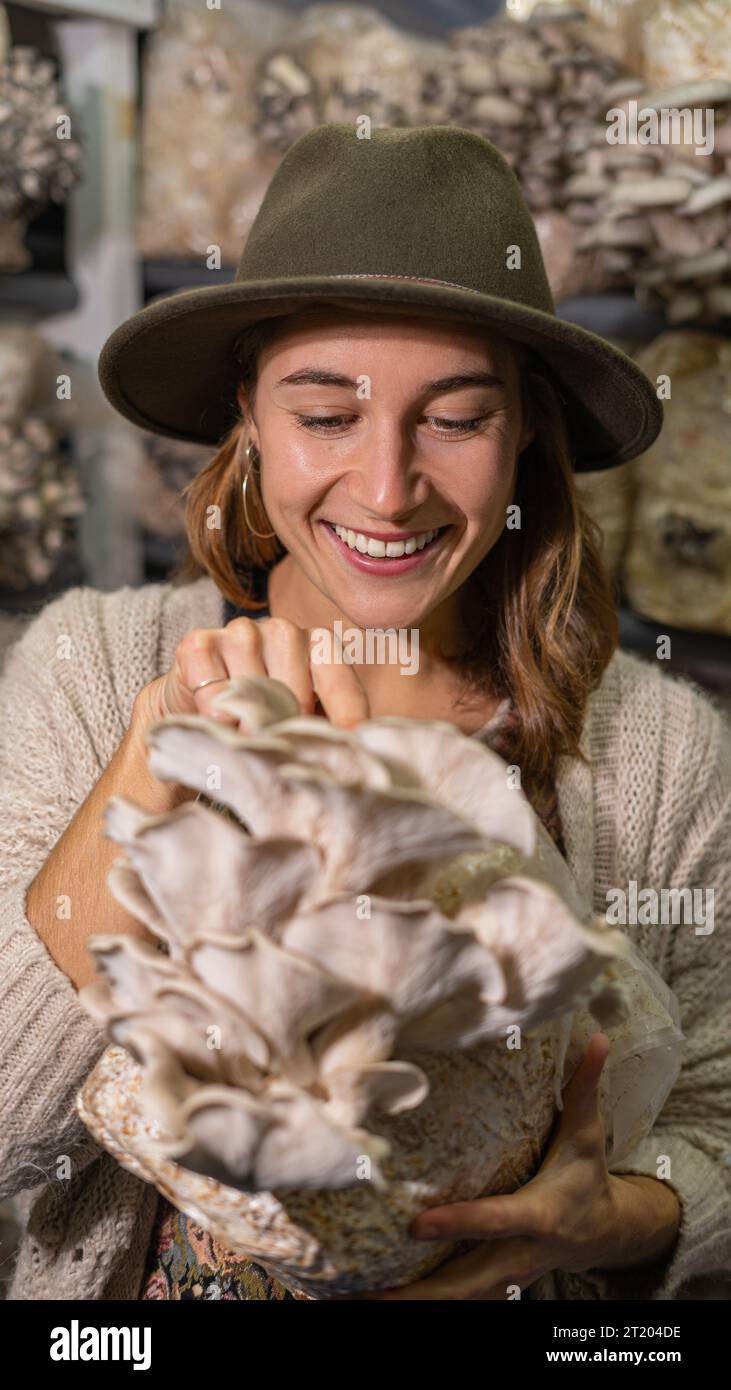 Giovane donna sorridente che tiene un terreno coltivato con funghi ostriche biologici Foto Stock