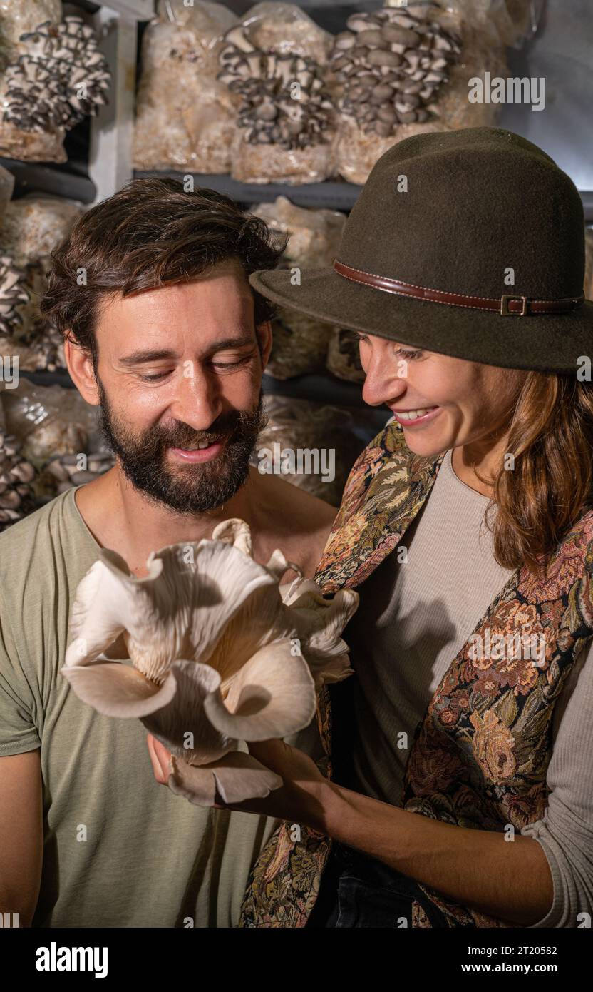 felice coppia contadina che tiene funghi ostriche in fattoria funghi Foto Stock