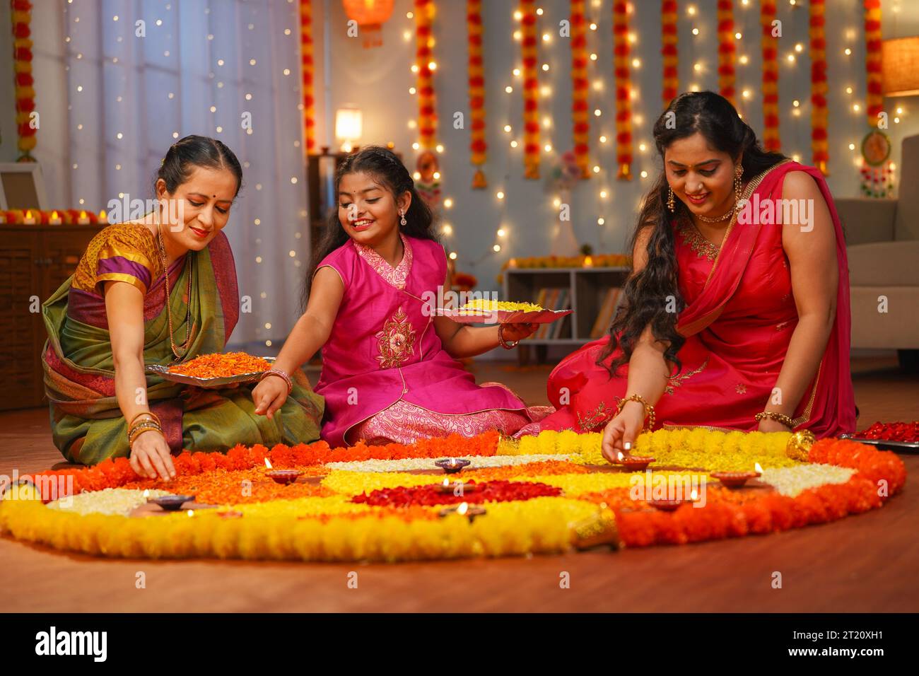 Gioiosa famiglia indiana multigenerazionale che prepara i rangoli diwali al piano per la celebrazione del festival diwali a casa - concetto di decorazione tradizionale Foto Stock