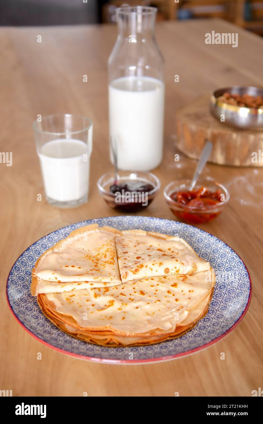 Dolci pancake rotondi sdraiati su un piatto rotondo accanto alla marmellata Foto Stock