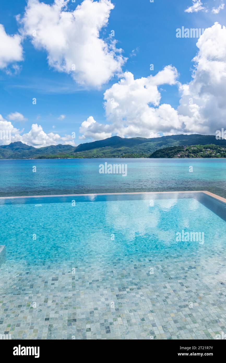 Piscina infinity con vista mare sull'isola tropicale. Foto Stock