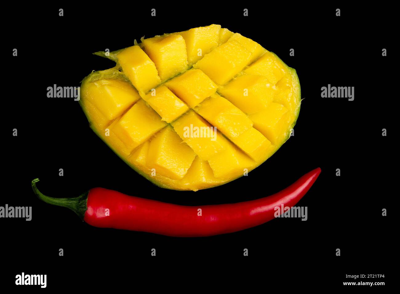 Metà tagliata di mango e peperoncino intero isolato su fondo nero puro Foto Stock