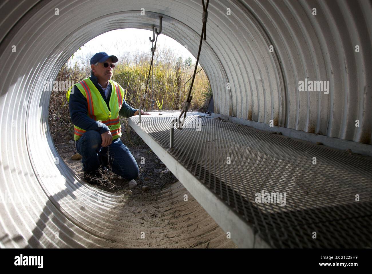 Un lavoratore del Montana ispeziona un passaggio di animali selvatici di nuova costruzione sotto un'autostrada, progettato per facilitare il movimento degli animali durante gli eventi in acqua alta. L'attraversamento garantisce una migrazione più sicura della fauna selvatica, riducendo al minimo i rischi di collisioni stradali e migliorando la connettività degli habitat. Foto Stock