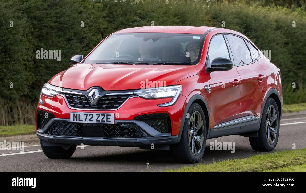 Bicester, Oxon., UK - 8 ottobre 2023: 2022 RED Renault Arkana RS line e-tech HEV auto elettrica ibrida che guida su una strada di campagna inglese. Foto Stock