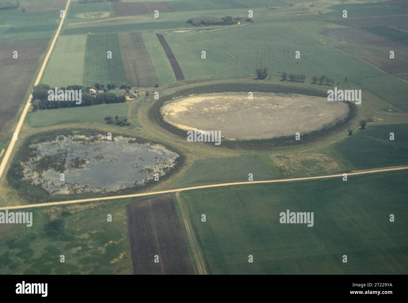 Un colpo aereo di una grande poppa semidrenata, separata da una strada. Il pozzo fa parte del paesaggio naturale, fornendo una prospettiva unica sulle caratteristiche geologiche e sui cambiamenti ambientali. Foto Stock