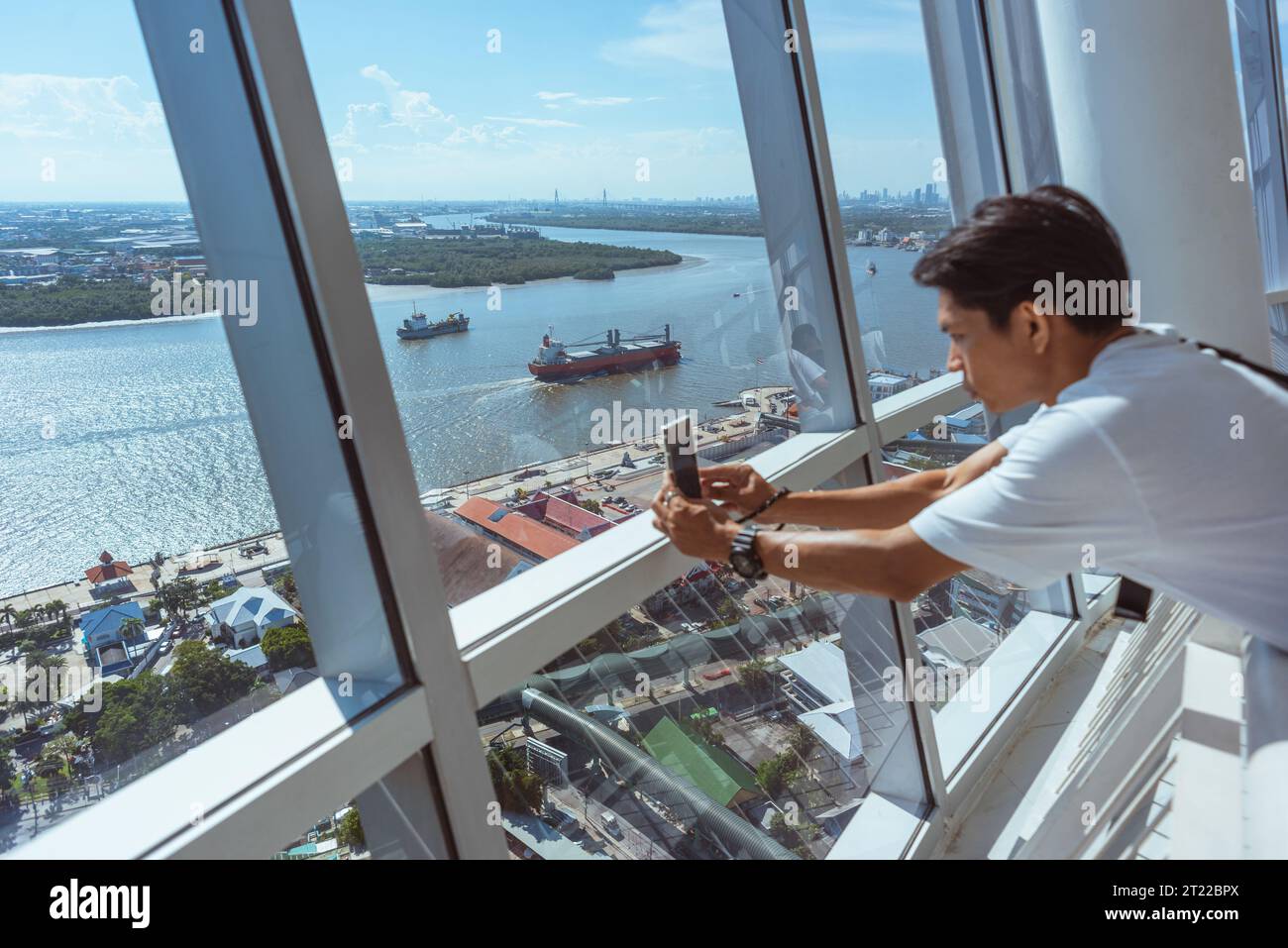 Samut Prakan, Thailandia - 3 settembre 2023: Un giovane (sfocato) scatta immagini da una piattaforma di osservazione della torre di Samut Prakan. Foto Stock