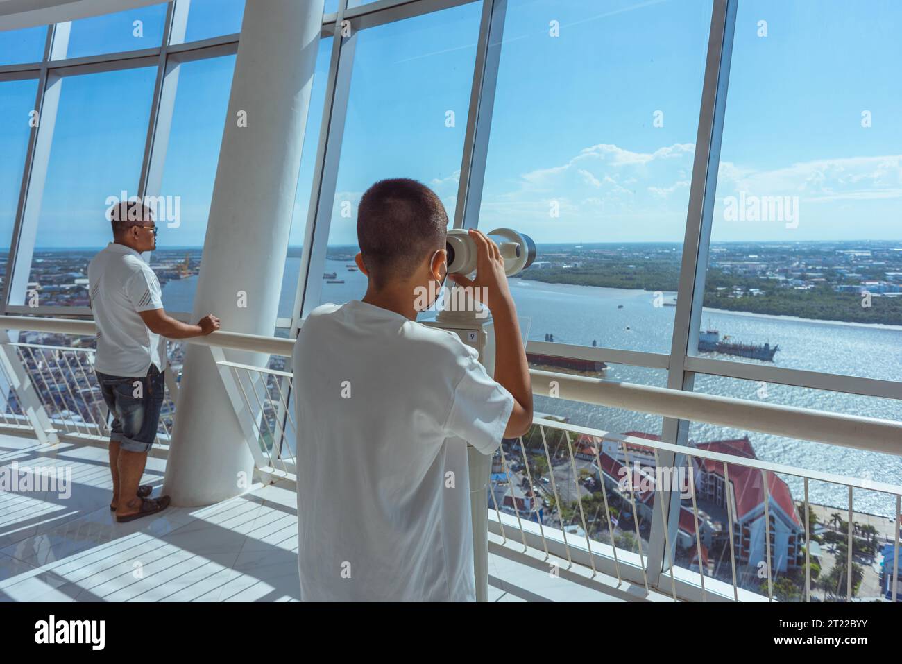 Samut Prakan, Thailandia - 3 settembre 2023: Un ragazzo guarda le rive del fiume Chao Phraya attraverso il binocolo presso la piattaforma di osservazione della torre di Samut Prakan Foto Stock