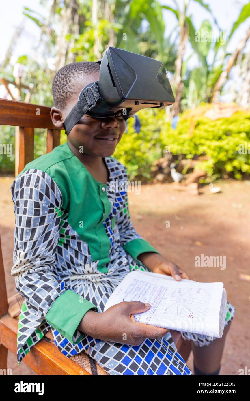 Foto verticale di un bambino che sta studiando usando cuffie per la realtà virtuale in Africa Foto Stock